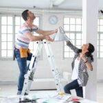Couple hanging a lamp in new apartment