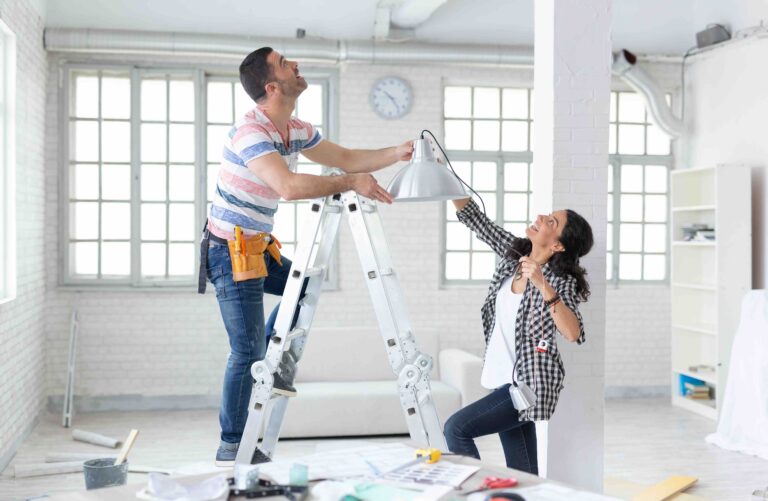 Couple hanging a lamp in new apartment