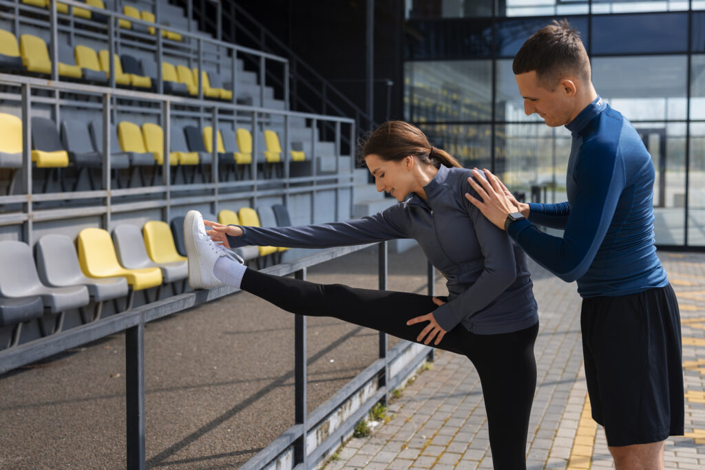 Athlete doing stretching with coach during sports performance training session outdoors