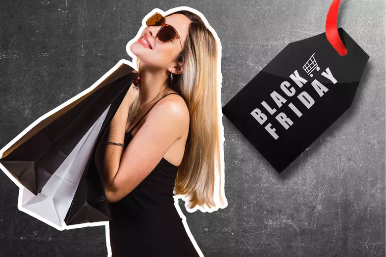 Woman smiling while holding shopping bags beside a sale tag that reads Black Friday, representing excitement for seasonal deals.