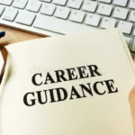 A person holding an open notebook with the words "Career Guidance" printed on the page, positioned next to a computer keyboard, representing modern career guidance for adults 2026.
