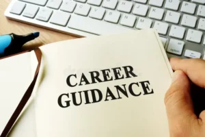 A person holding an open notebook with the words "Career Guidance" printed on the page, positioned next to a computer keyboard, representing modern career guidance for adults 2026.