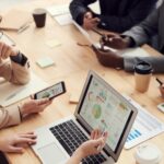 Team of professionals discussing SEO strategy and digital marketing plans around a conference table with charts and laptop.