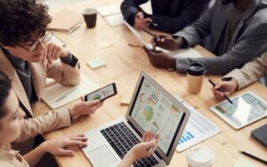 Team of professionals discussing SEO strategy and digital marketing plans around a conference table with charts and laptop.