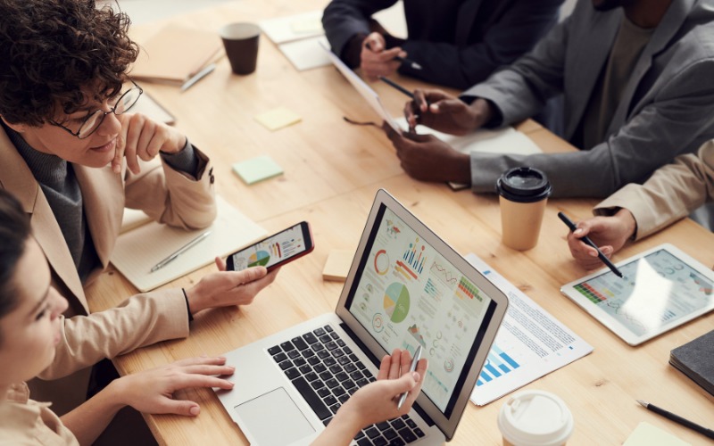 Team of professionals discussing SEO strategy and digital marketing plans around a conference table with charts and laptop.
