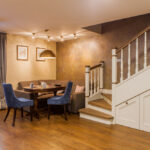 Cozy finished basement with wooden flooring, dining area, upholstered seating, and staircase with white railing and built-in storage underneath