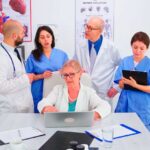 mature-doctor-specialist-briefing-her-medical-team-conference-room-using-laptop-medical-team-teamwork-people-discussing-diagnosis-about-patients-treatment-issues-record-workplace2