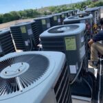 Commercial rooftop HVAC air conditioning units being serviced by a technician for professional AC repair and maintenance.