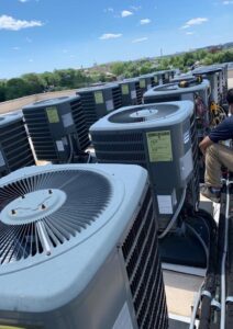 Commercial rooftop HVAC air conditioning units being serviced by a technician for professional AC repair and maintenance.