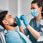 Dentistry, medicine. A female dentist in a mask treats a patient's teeth.