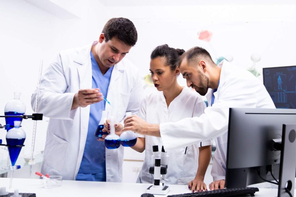 team-scientist-white-coat-working-together-with-smoking-blue-liquid-modern-research-lab (1)