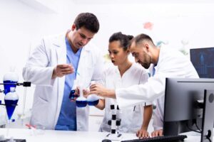 team-scientist-white-coat-working-together-with-smoking-blue-liquid-modern-research-lab (1)
