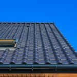 Vertical low angle closeup shot of the black roof of a building with a blue background