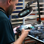 Technician inspecting industrial smart camera hardware during electronics manufacturing quality control.