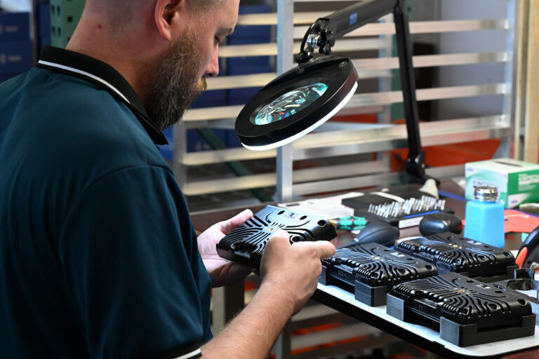 Technician inspecting industrial smart camera hardware during electronics manufacturing quality control.