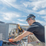 Hvac tech working on a condensing unit rooftop outside