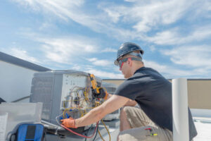 Hvac tech working on a condensing unit rooftop outside