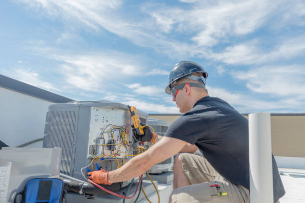 Hvac tech working on a condensing unit rooftop outside