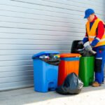 Janitor takes garbage out of trash container outdoors in the street