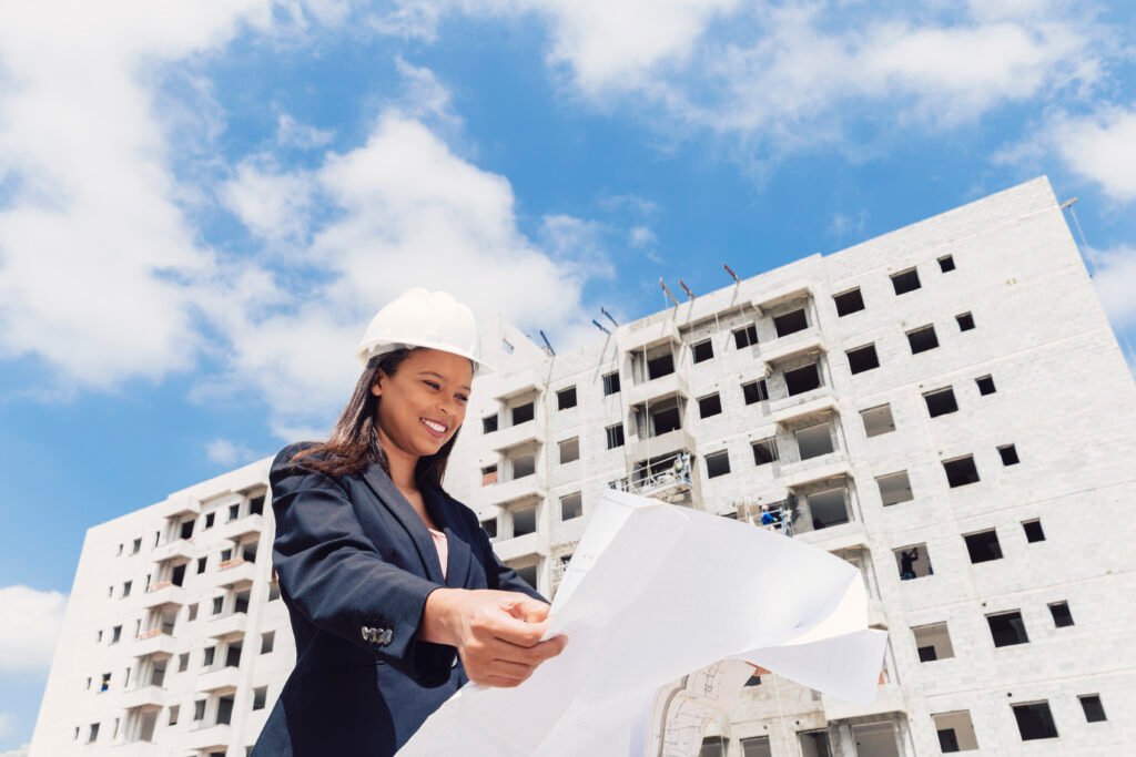 happy-african-american-lady-safety-helmet-with-paper-plan-near-building-construction