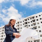 happy-african-american-lady-safety-helmet-with-paper-plan-near-building-construction