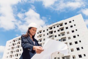 happy-african-american-lady-safety-helmet-with-paper-plan-near-building-construction