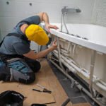 Man servicing the pipe system of a bathtub with hydromassage.